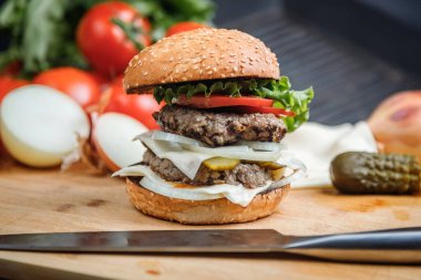 Sığır eti, peynir ve sebzeli leziz ızgara burger. Koyu arkaplanda nefis ızgara çizburger.. 