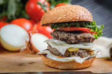 Sığır eti, peynir ve sebzeli leziz ızgara burger. Koyu arkaplanda nefis ızgara çizburger.. 