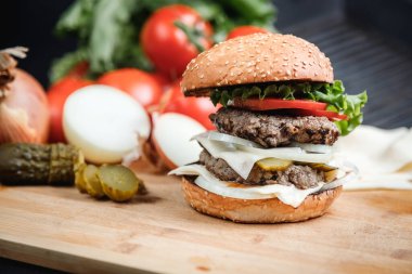 Sığır eti, peynir ve sebzeli leziz ızgara burger. Koyu arkaplanda nefis ızgara çizburger.. 