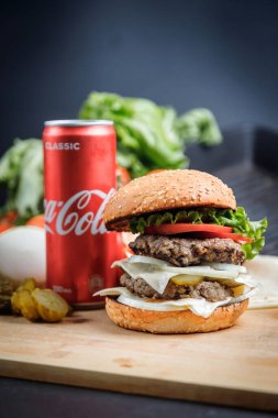Rusya, Moskova - 5 Ekim 2020. Peynirli hamburger, domates, marul, sos ve bir kutu Coca-Cola..