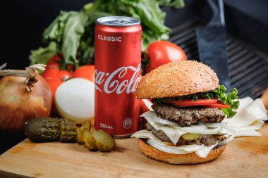 Rusya, Moskova - 5 Ekim 2020. Peynirli hamburger, domates, marul, sos ve bir kutu Coca-Cola..