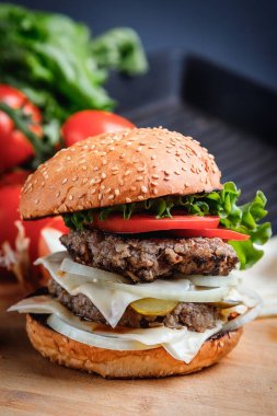 Sığır eti, peynir ve sebzeli leziz ızgara burger. Koyu arkaplanda nefis ızgara çizburger.. 