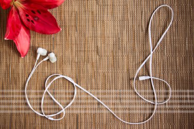 Bir müzikal olay için boş kopyalama alanı ile nötr kahverengi arka plan. Kayıttaki müzik kavramı. Bir tiz clef şeklinde güzel bir çiçek ve kulaklık. Düz döşeme, üst görünüm