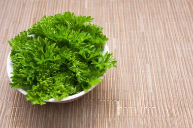 Bej arka planda beyaz tabakta yeşil maydanoz ve fotokopi alanı. Sağlıklı yaşam tarzı.