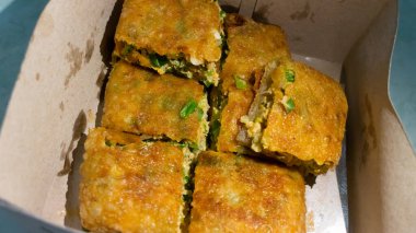 Martabak Telor. Yumurta, kıyma ve baharatla doldurulmuş tuzlu tavada kızartılmış hamur işi. Martabak kare şeklinde kesilir ve gözyaşı şeklinde seramik tabakta salatalık-acı biber ile servis edilir.