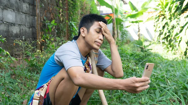 Aziatische Man Tuinieren Verdrietig Terwijl Kijken Naar Zijn Mobiele Telefoon — Stockfoto