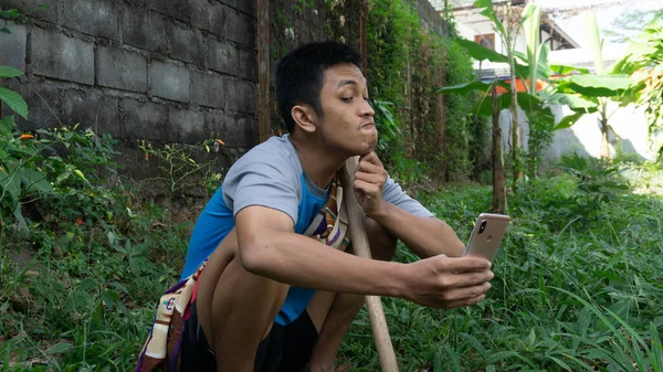 Aziatisch Man Tuinieren Denken Terwijl Het Kijken Naar Zijn Mobiele — Stockfoto