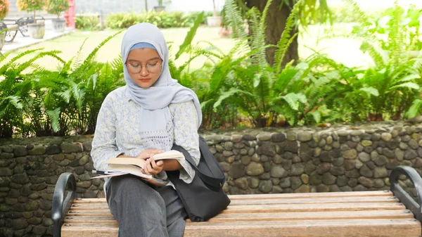 Asian hijab girl reading in the campus garden