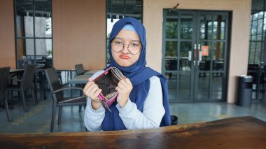 Asyalı kadın boş bir cüzdan görünce üzülüyor.