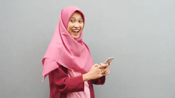若いアジアのイスラム教徒の女性の肖像画ヒジャーブを身に着けている彼女の電話で良いニュースを取得 幸せな驚きの表現 — ストック写真