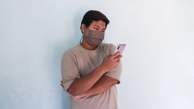 Asyalı şişman adam oynuyor ve cep telefonunun maskesini görüyor.