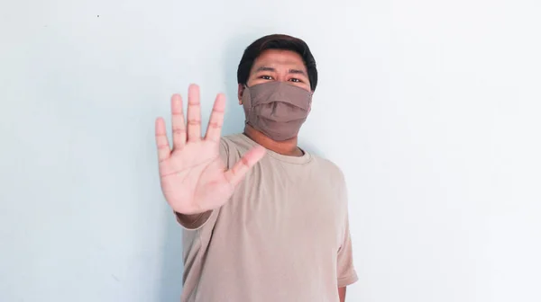 Portrait of a asian fat man in a medical mask show stop hand gesture
