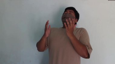 Maske takan Asyalı şişman adam öksürüyor.