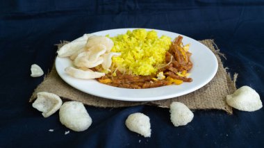 Nasi kuning veya sarı pirinç, Endonezya 'dan geleneksel yemek, kahvaltı için wiith yumurtası, tempeh ve kraker veya kerupuk' u birleştirin.