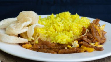 Nasi kuning veya sarı pirinç, Endonezya 'dan geleneksel yemek, kahvaltı için wiith yumurtası, tempeh ve kraker veya kerupuk' u birleştirin.