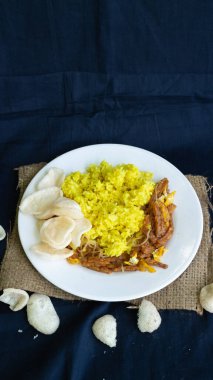 Nasi kuning veya sarı pirinç, Endonezya 'dan geleneksel yemek, kahvaltı için wiith yumurtası, tempeh ve kraker veya kerupuk' u birleştirin.