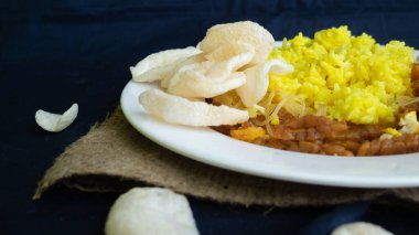 Nasi kuning veya sarı pirinç, Endonezya 'dan geleneksel yemek, kahvaltı için wiith yumurtası, tempeh ve kraker veya kerupuk' u birleştirin.