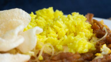 Nasi kuning veya sarı pirinç, Endonezya 'dan geleneksel yemek, kahvaltı için wiith yumurtası, tempeh ve kraker veya kerupuk' u birleştirin.