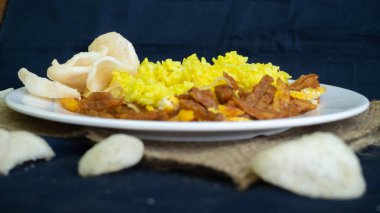 Nasi kuning veya sarı pirinç, Endonezya 'dan geleneksel yemek, kahvaltı için wiith yumurtası, tempeh ve kraker veya kerupuk' u birleştirin.