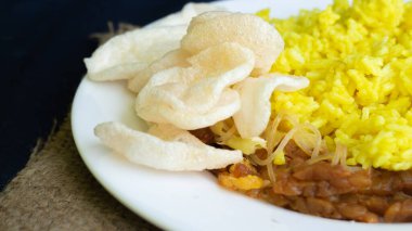 Nasi kuning veya sarı pirinç, Endonezya 'dan geleneksel yemek, kahvaltı için wiith yumurtası, tempeh ve kraker veya kerupuk' u birleştirin.