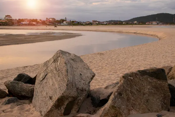 Landscape of a beach with golden sand and large stones, natural lake formed by the waters of the ocean. End of the day, sunset Brazilian beach