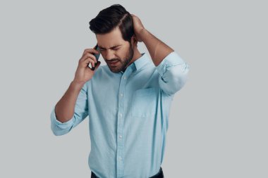 Hoş olmayan bir konuşma. Şaşkın genç adam akıllı telefon w konuşuyor