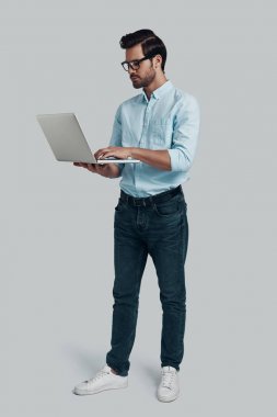 Net sörf. Tam uzunluğu genç adam kullanarak Laptop süre STA