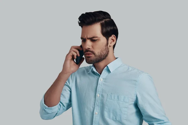 Bad news. Confused young man talking on the smart phone while st — Stock Photo, Image