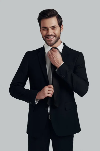 Perfect style. Handsome young man in full suit adjusting tie and — Stock Photo, Image