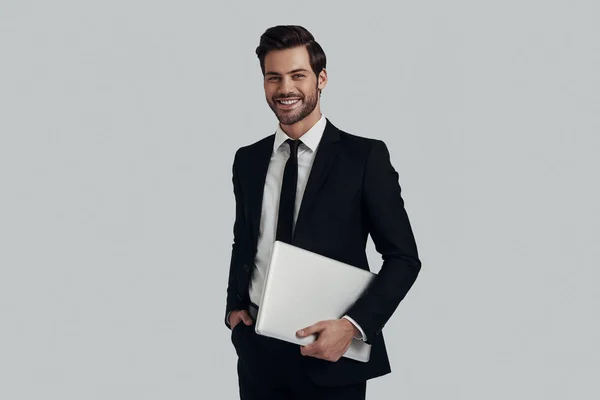 Modern businessman. Handsome young man in full suit carrying lap — Stock Photo, Image