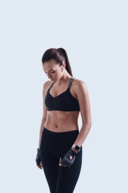 Her zaman harika bir şekle sahiptir. Çekici genç kadın uzak gri arka planda ayakta bakıyor