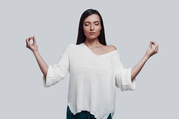 Ruhe bewahren. attraktive junge Frau meditiert vor grauem Hintergrund — Stockfoto