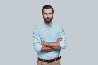 Mükemmel adam. Yakışıklı genç adam kamera bakıyor ve gri arka planda ayakta iken gülümsüyor