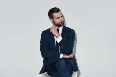 Düşünmek için zaman ayırdığınız. Gri arka plana karşı otururken yakışıklı genç adam uzak bakıyor