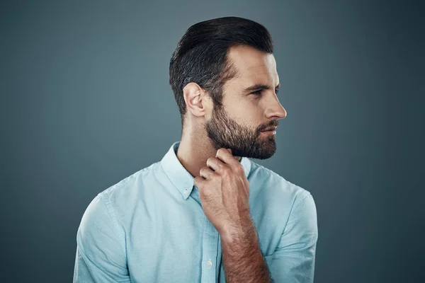 Thinking about... Handsome young man smiling and looking away while standing against grey background — Stock Photo, Image