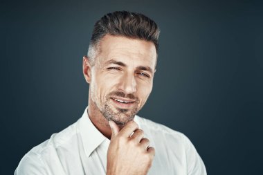 Neşeli adam. Yakışıklı genç adam gülümseyerek ve gri arka plan karşı dururken kameraya bakıyor