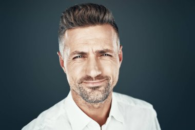 Neşeli ve yakışıklı. Yakışıklı genç adam gülümseyerek ve gri arka plan karşı dururken kameraya bakıyor
