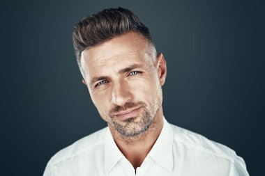 Mükemmel bir adam. Yakışıklı genç adam gülümseyerek ve gri arka plan karşı dururken kameraya bakıyor