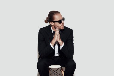 Düşünme zamanı. Gri arka plan aleyhine otururken tam takım elbiseli Charming genç adam uzağa bakıyor