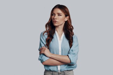 Düşüncelerde kaybolmuş. Gri arka planda dururken uzağa bakan güzel genç kadın