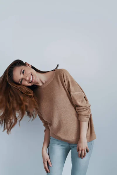 Cabelo forte. Mulher bonita olhando para a câmera e sorrindo enquanto estava de pé contra o fundo cinza — Fotografia de Stock