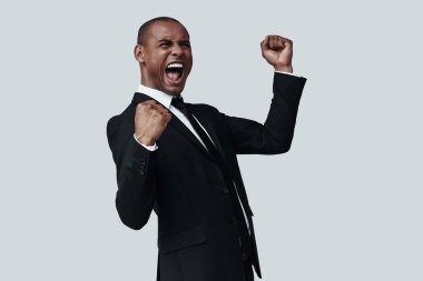 Ben yaptım! Gri arka plan aleyhine dururken formalwear gesturing ve bağırarak yakışıklı genç Afrikalı adam