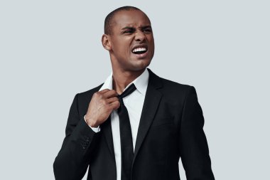 Overworked. Gri arka plan aleyhine dururken kravatını çıkararak formalgiyimli yorgun genç Afrikalı adam