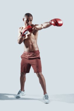 Güç ve güç. Gri arka plan aleyhine dururken mücadele kırmızı boks eldivengenç Afrikalı adam tam uzunlukta