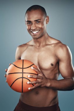 Basketbolcu. Yakışıklı gömleksiz Afrikalı adam kameraya bakıyor ve gri arka plan karşı dururken gülümseyerek