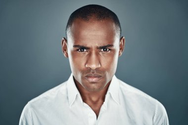 Kızgın hissediyorum. Gri arka plan aleyhine dururken kameraya bakan ve kaşlarını çatarak gömlekli genç Afrikalı adam memnun değil