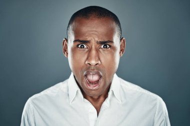 Ne?! Gri arka plan karşısında dururken kameraya bakan ve bir yüz yapma gömlek şok genç Afrikalı adam