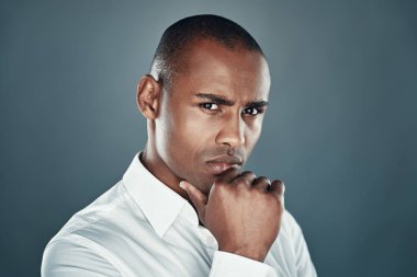 Saf güven. Gri arka plan aleyhine dururken kamera ya da çeneüzerinde el tutmak gömlek yakışıklı genç Afrikalı adam