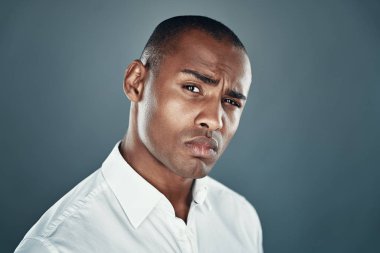 Erkeklik. Gri arka plan aleyhine dururken kamera ve kaşlarını çatma görünümlü gömlek yakışıklı genç Afrikalı adam