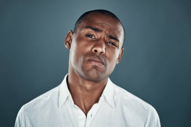 Kendinden emin bir görünüm. Gri arka plan aleyhine dururken kamera ve kaşlarını çatma görünümlü gömlek yakışıklı genç Afrikalı adam